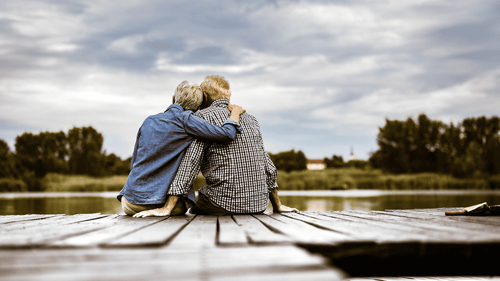Back view of a seated couple looking out across a river