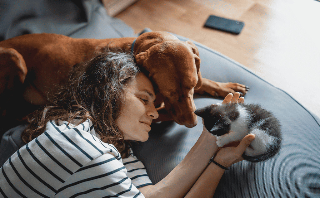 woman with older dog, cradling a kitten